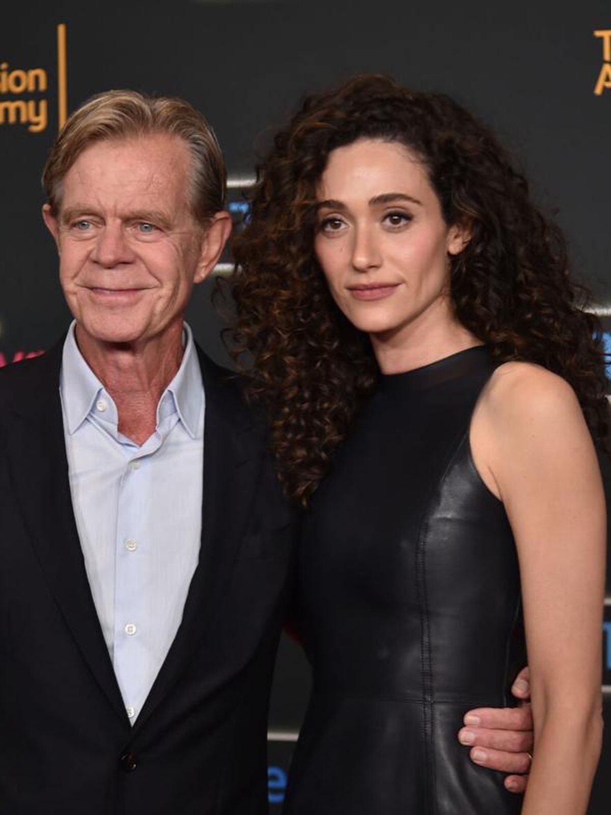 Emmy Rossum and William H Macy standing together on a step and repeat backdrop